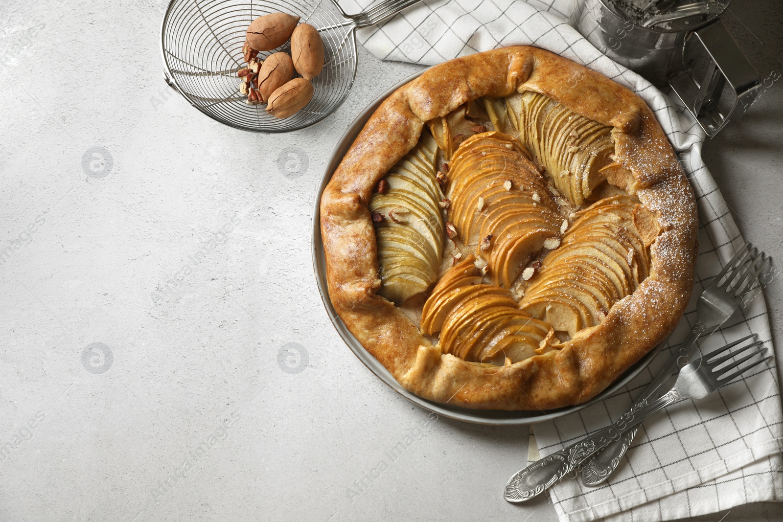 Photo of Delicious apple galette with pecans and forks on light gray textured table, flat lay. Space for text