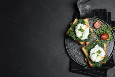 Photo of Delicious poached egg sandwiches served on black table, flat lay. Space for text