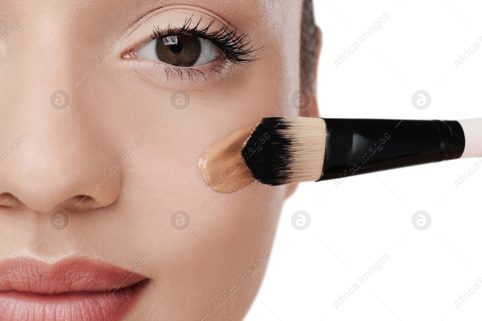 Photo of Woman applying foundation on face with brush against white background, closeup