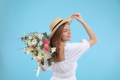 Photo of Beautiful woman in straw hat with bouquet of flowers on light blue background