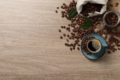 Photo of Cup of aromatic hot coffee and beans on wooden table, flat lay. Space for text