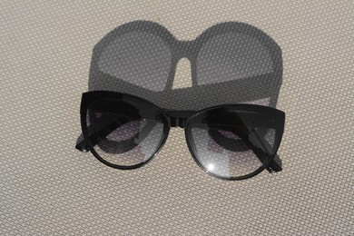 Photo of Stylish sunglasses on grey surface. Beach accessory, top view