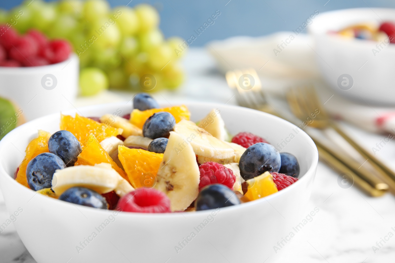 Photo of Fresh tasty fruit salad on white marble table, closeup