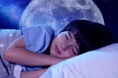 Cute little boy sleeping in bed and beautiful starry sky with full moon at night on background