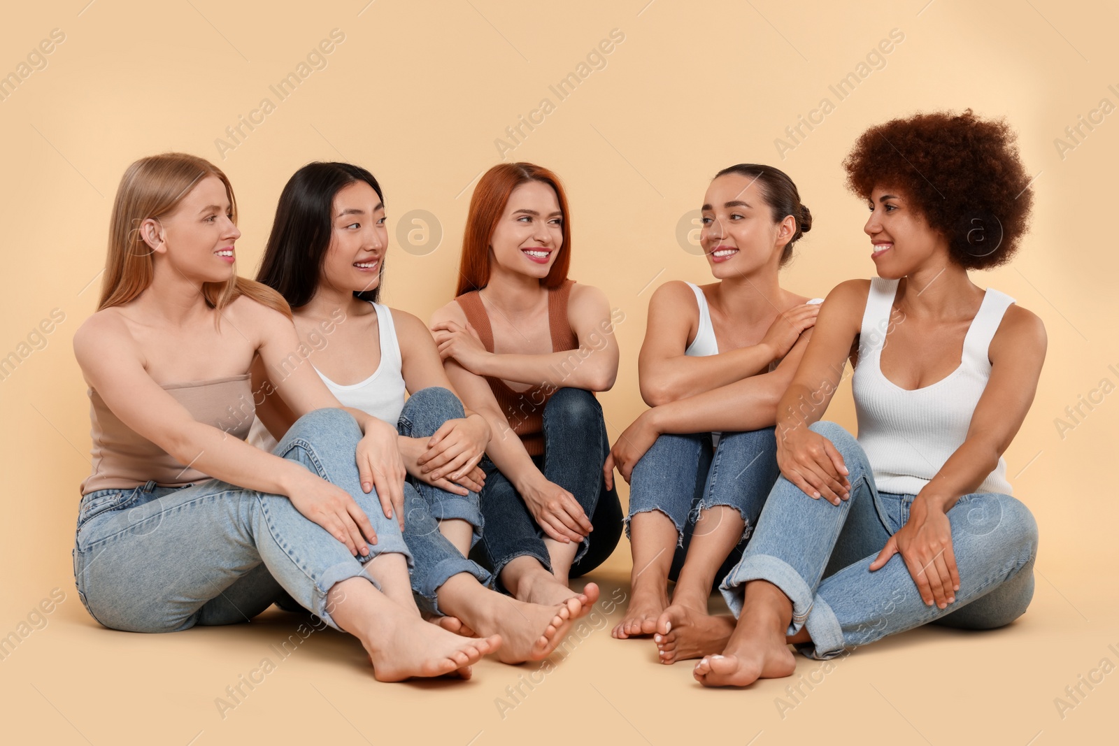 Photo of Group of beautiful young women sitting on beige background