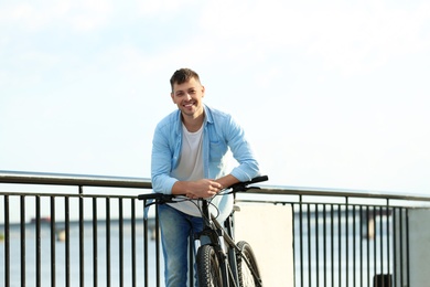 Photo of Handsome man with modern bicycle near river