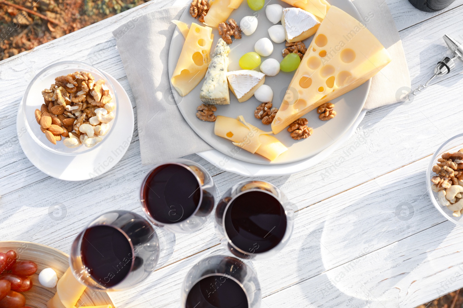 Photo of Flat lay composition with wine and cheese on white wooden table outdoors