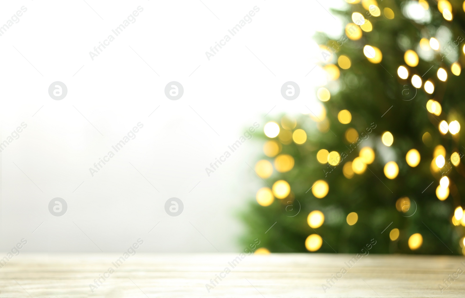 Photo of Empty table and blurred fir tree with yellow Christmas lights on background, bokeh effect. Space for design