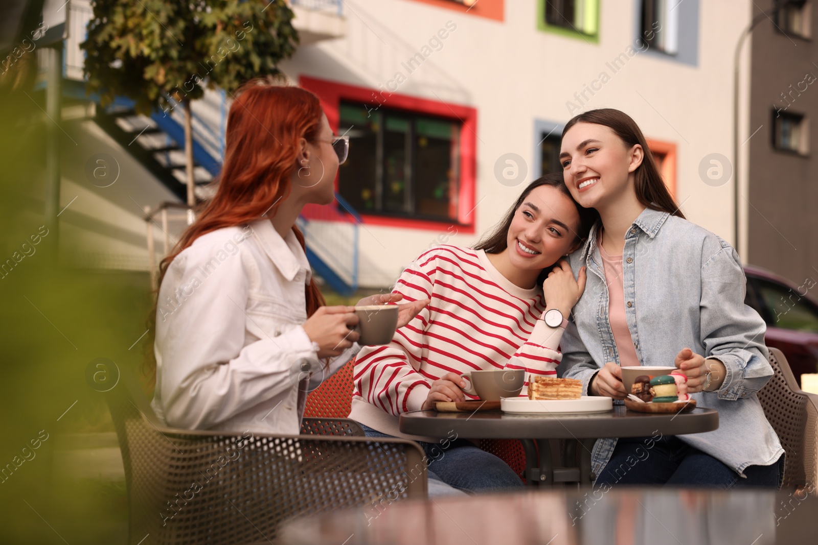 Photo of Happy friends talking and drinking coffee in outdoor cafe