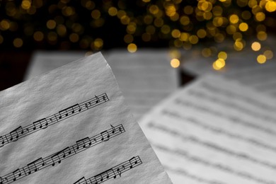 Closeup view of note sheet against blurred lights. Christmas music