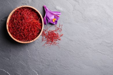 Photo of Dried saffron and crocus flower on grey table, flat lay. Space for text