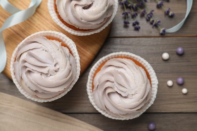 Photo of Tasty cupcakes on wooden table, flat lay