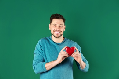 Photo of Man holding decorative heart on color background