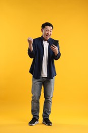 Photo of Full length portrait of happy man with smartphone on yellow background