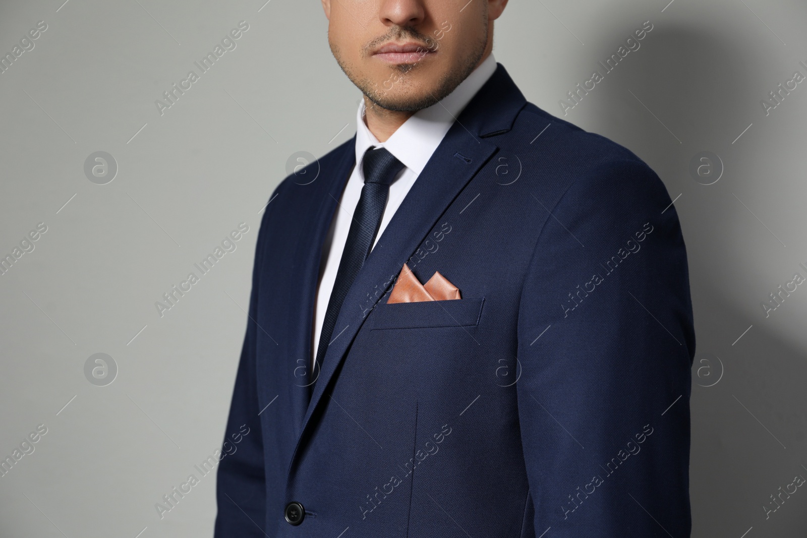 Photo of Man with handkerchief in breast pocket of his suit on light grey background, closeup