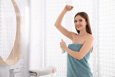 Photo of Beautiful young woman applying deodorant after shower in bathroom