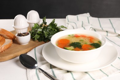 Photo of Delicious vegetable soup with noodles served on white wooden table