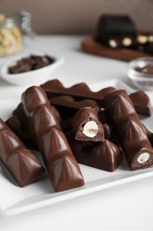 Photo of Tasty chocolate bars with nuts on white wooden table, closeup