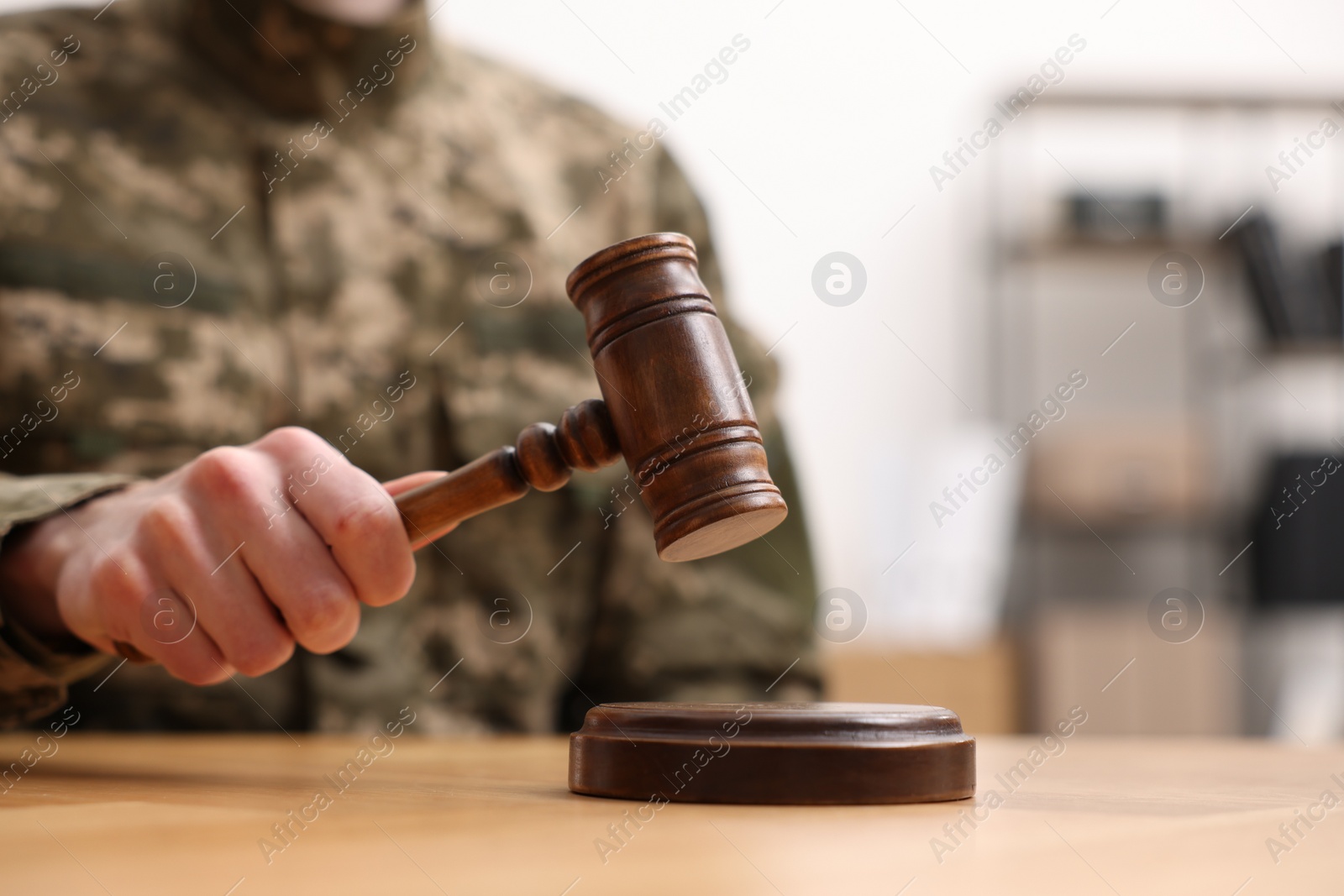 Photo of Law concept. Man in military uniform with gavel at wooden table, closeup. Space for text