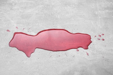 Puddle of red liquid on light grey surface