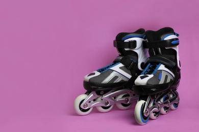 Photo of Pair of inline roller skates on color background. Space for text