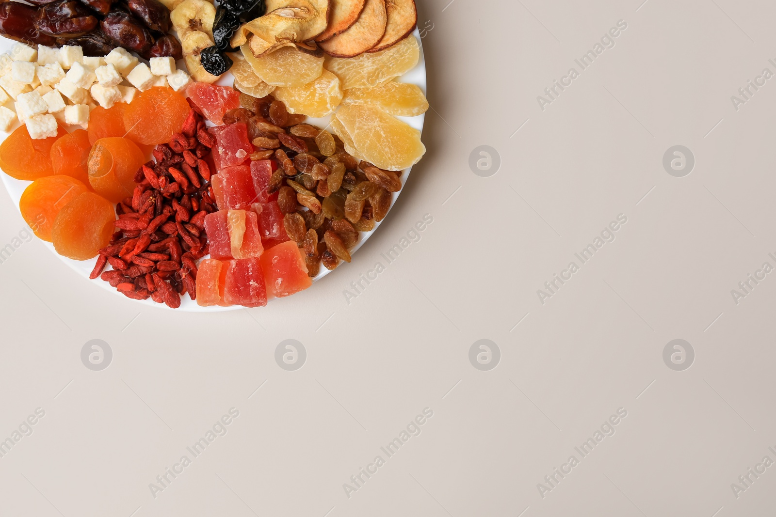 Photo of Plate with different dried fruits on white background, top view. Space for text