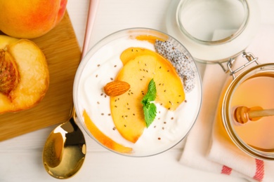 Photo of Tasty peach dessert with yogurt and chia seeds served on white wooden table, flat lay