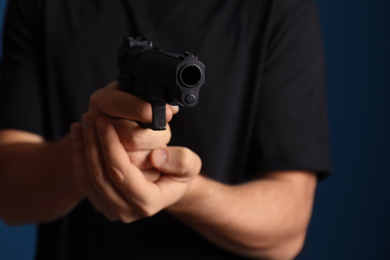 Photo of Man holding gun on dark background, closeup