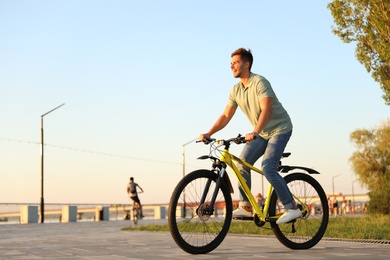 Handsome young man riding bicycle on city waterfront