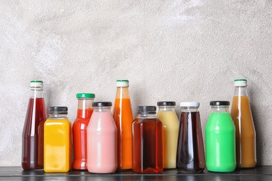 Bottles with different drinks on table against color background