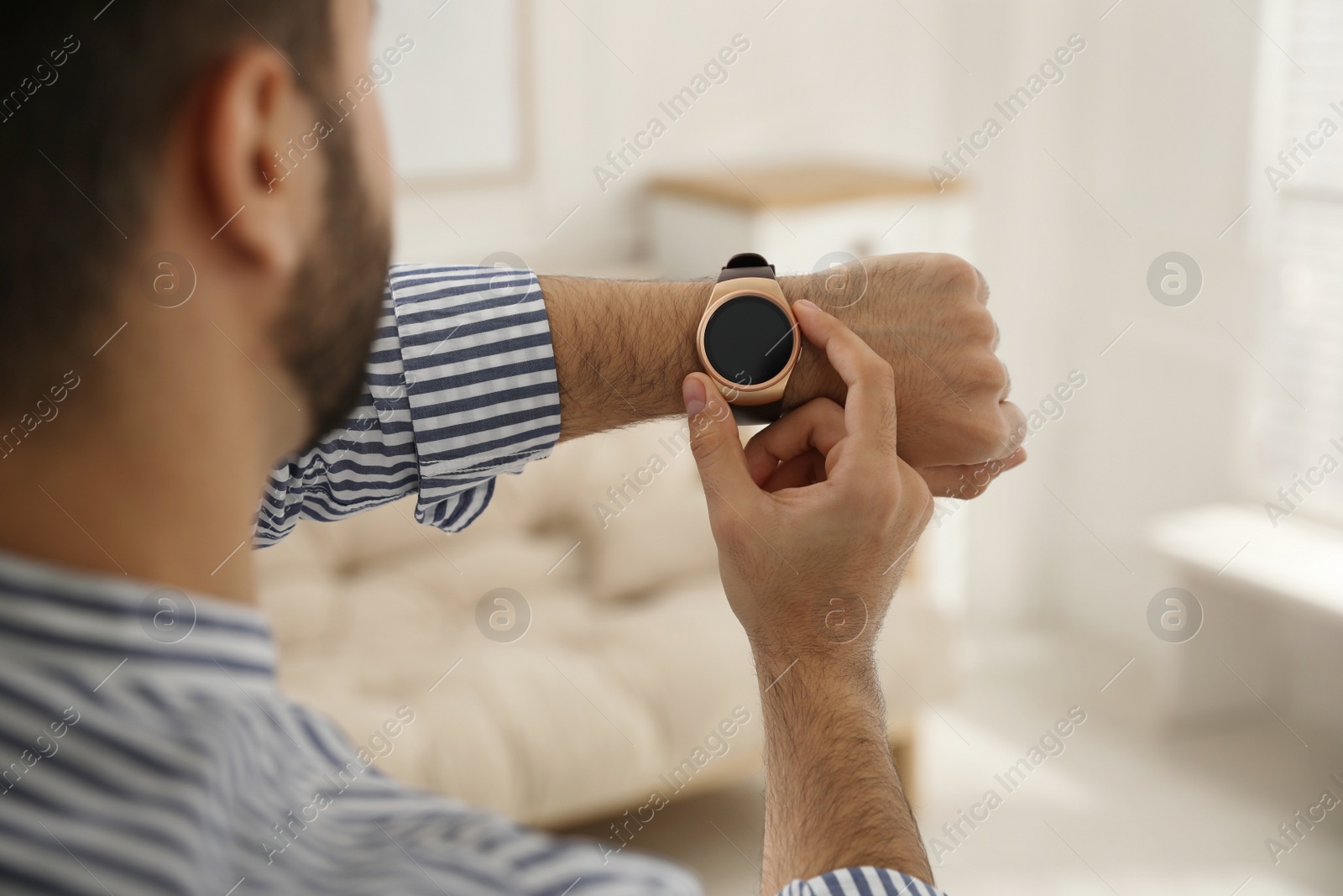 Photo of Man checking smart watch at home, closeup