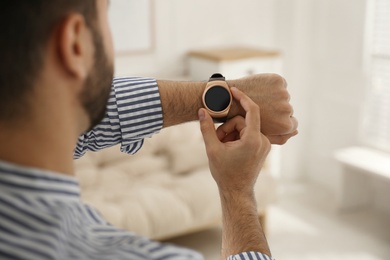 Photo of Man checking smart watch at home, closeup