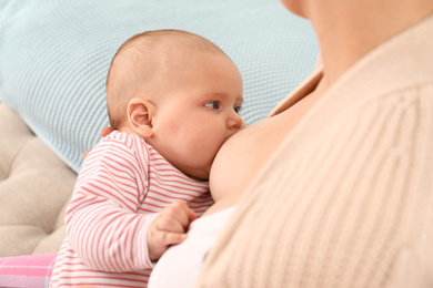 Photo of Young woman breastfeeding her little baby at home, closeup