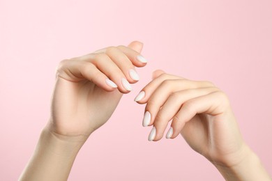 Photo of Woman with white polish on nails against pink background, closeup
