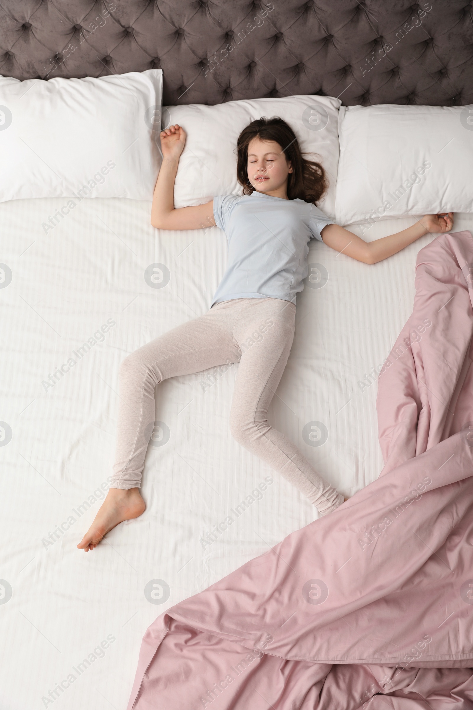 Photo of Cute little girl sleeping in bed, top view