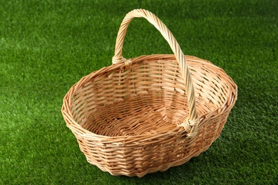 Photo of New empty wicker basket on green lawn. Easter item