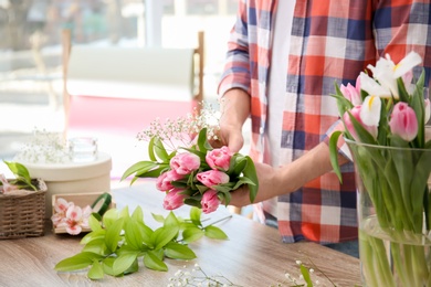 Photo of Male decorator creating beautiful bouquet at table