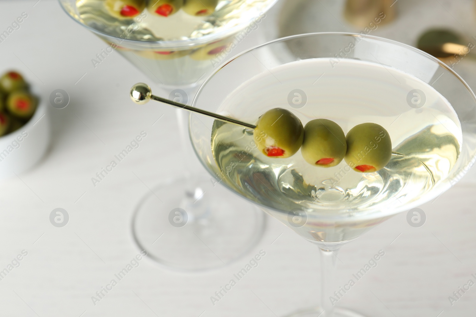 Photo of Glasses of Classic Dry Martini with olives on wooden table, closeup