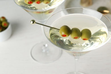 Photo of Glasses of Classic Dry Martini with olives on wooden table, closeup