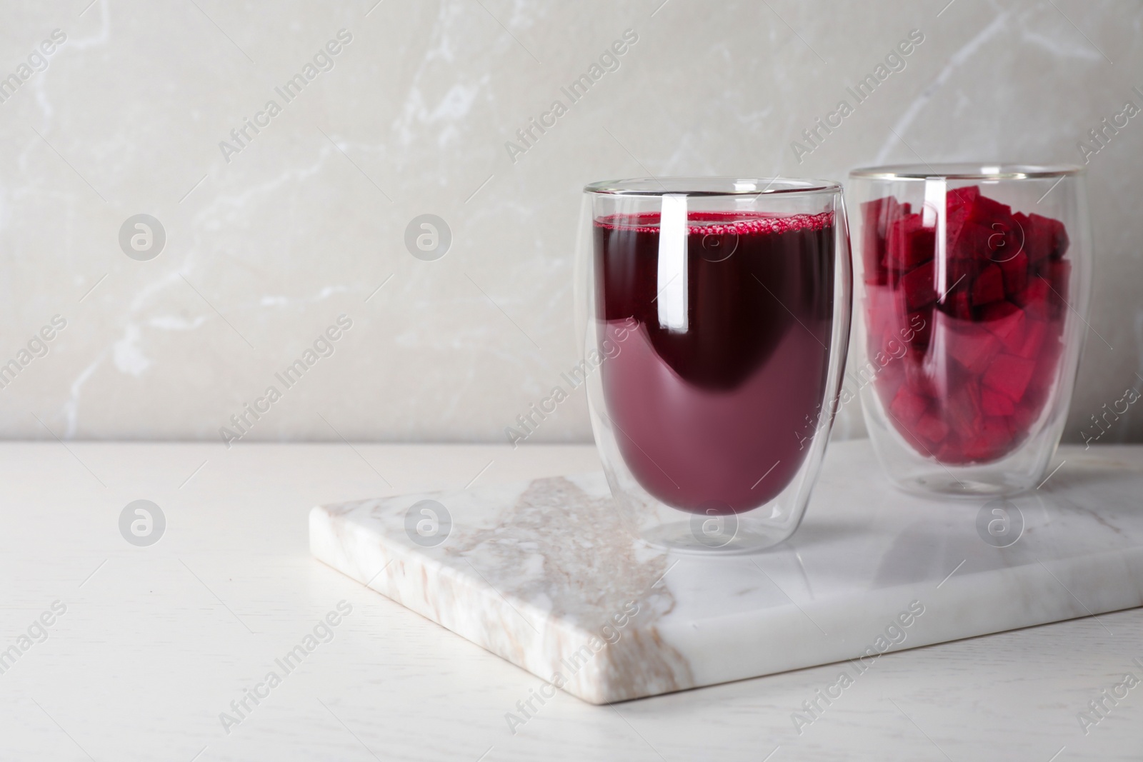 Photo of Glasses with fresh beet juice and cut vegetable on marble board