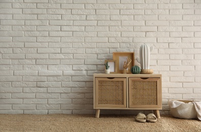 Photo of Stylish room interior with wooden cabinet near white brick wall. Space for text