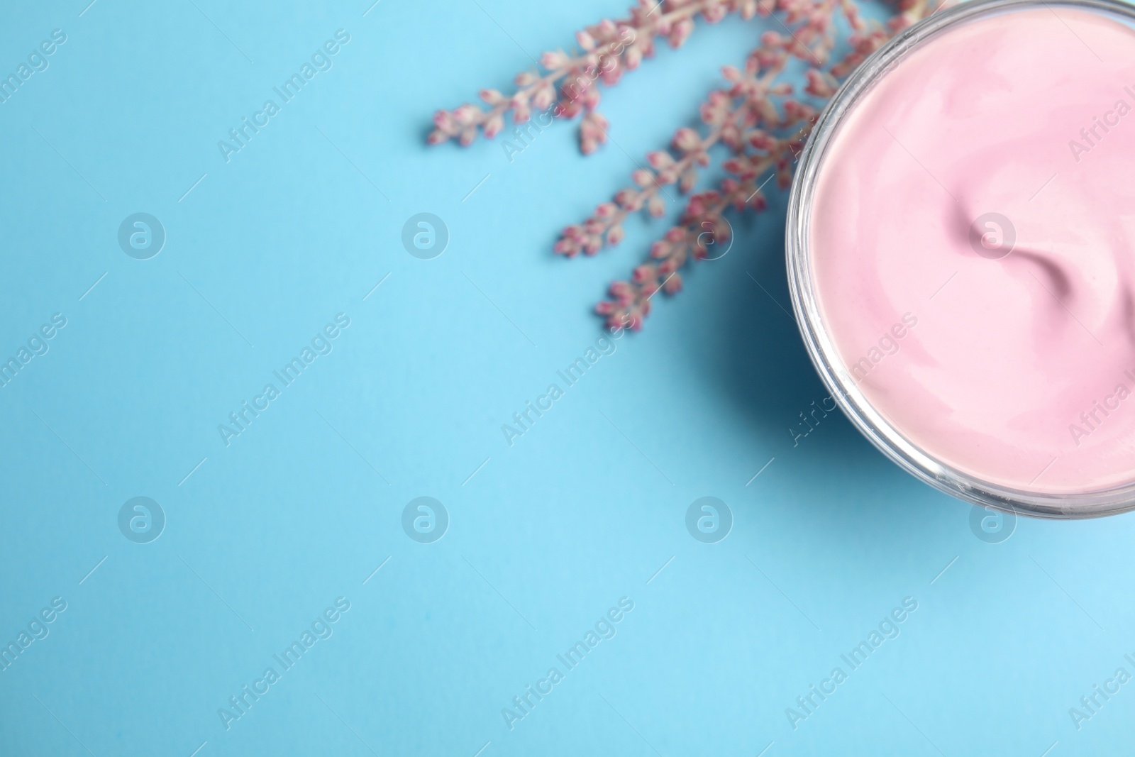 Photo of Professional face mask with flowers on light blue background, flat lay. Space for text