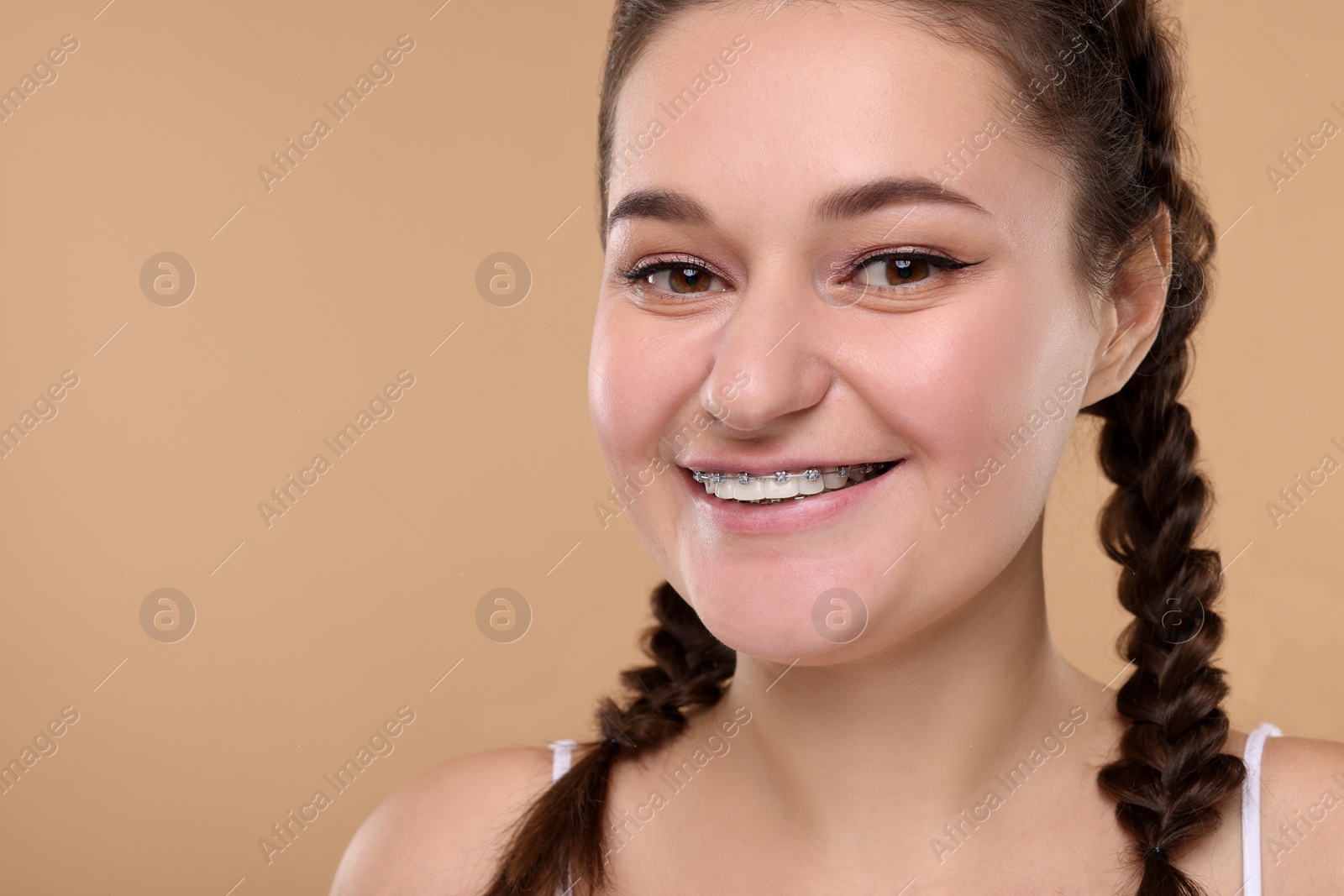 Photo of Smiling woman with braces on beige background. Space for text