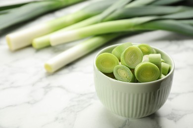 Cut fresh raw leek in bowl on white marble table, closeup. Space for text