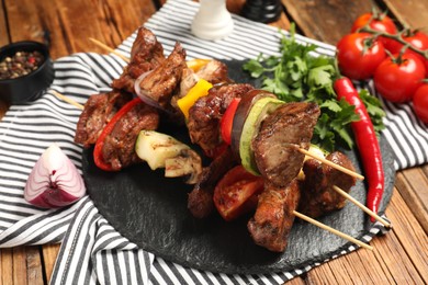 Photo of Delicious shish kebabs with vegetables on wooden table