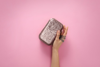 Woman holding stylish handbag on pink background, closeup