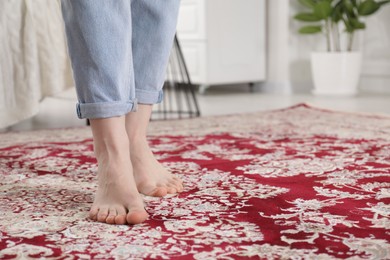 Photo of Woman standing on carpet with pattern at home, closeup. Space for text