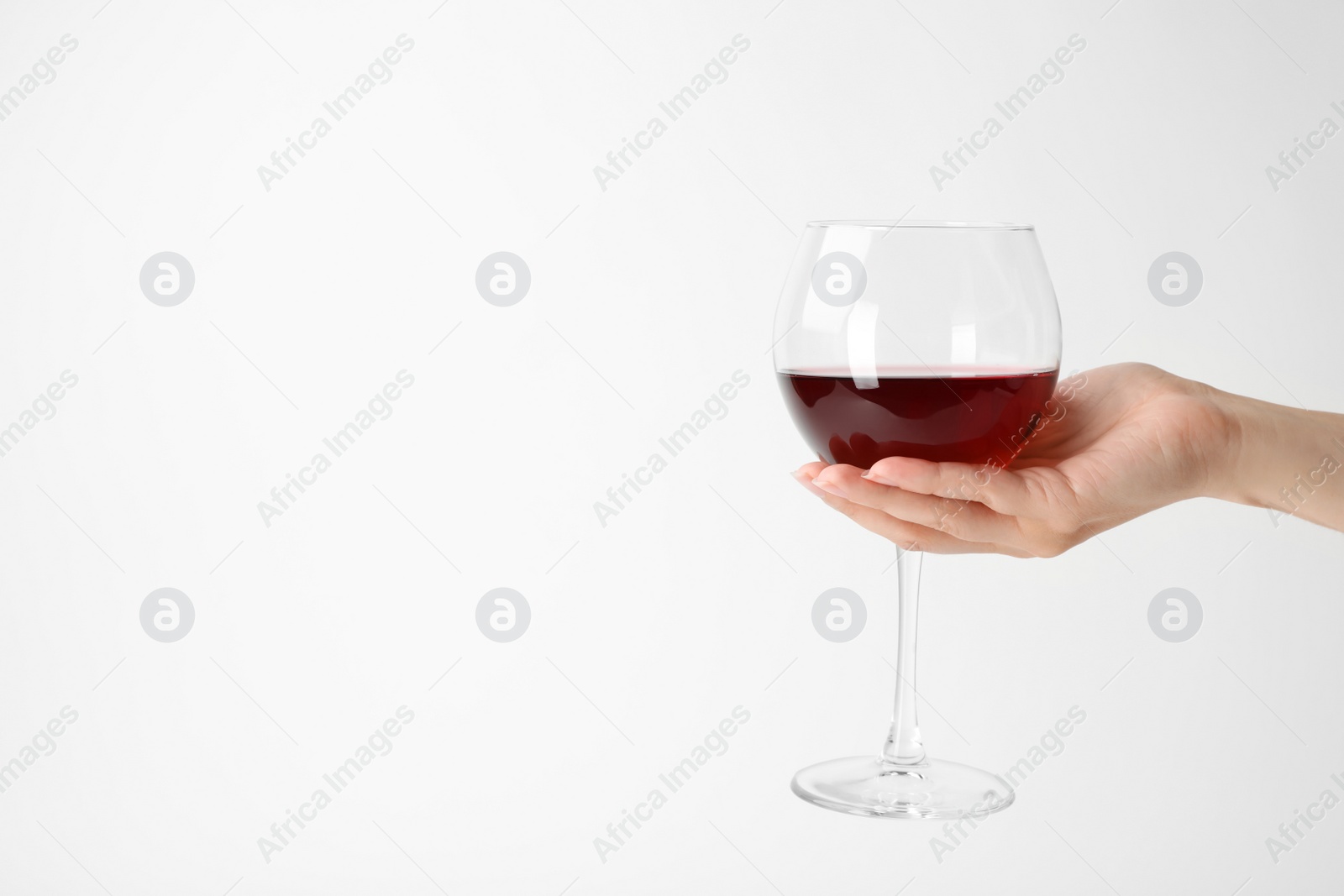 Photo of Woman holding glass of expensive red wine on white background