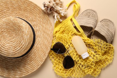 String bag and different beach accessories on beige background, top view