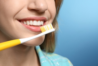 Photo of Young woman with toothbrush on color background, closeup. Space for text